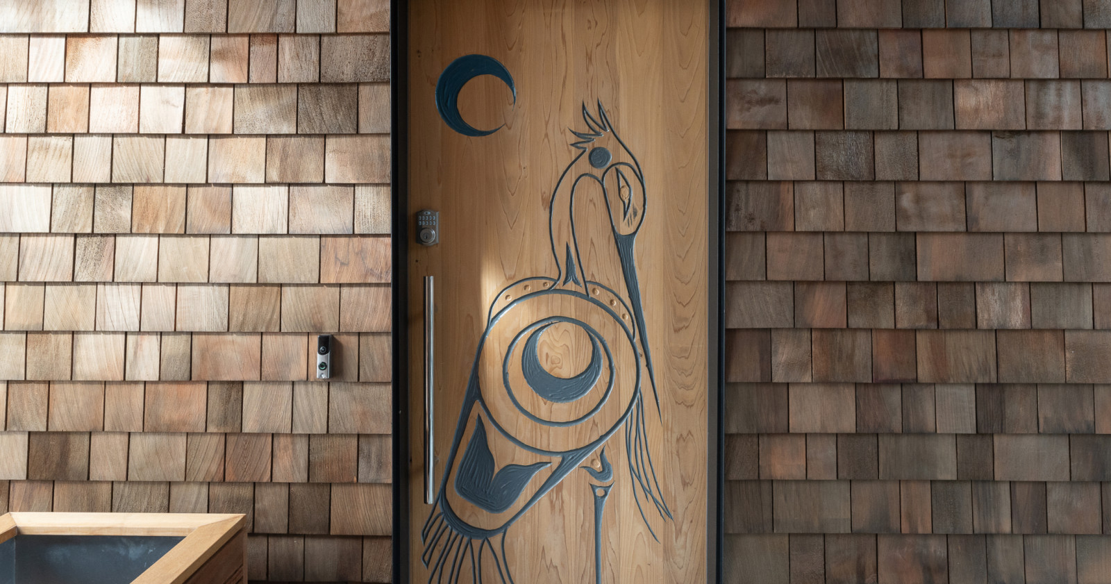 Custom carved door and natural cedar shingles elevate the character of the home
