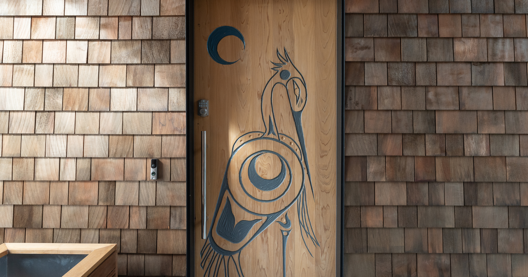 Custom carved door and natural cedar shingles elevate the character of the home